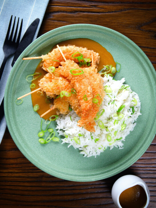 Overhead crispy king prawn katsu curry served with spring onion rice.