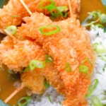 Overhead close-up crispy king prawn katsu curry served with spring onion rice.