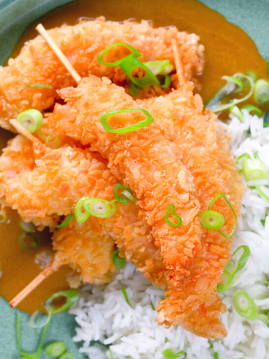 Overhead close-up crispy king prawn katsu curry served with spring onion rice.