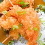 Overhead close-up crispy king prawn katsu curry served with spring onion rice.