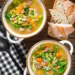 Overhead Scotch broth soup with lamb, pearl barley and savoy cabbage, served with bread.
