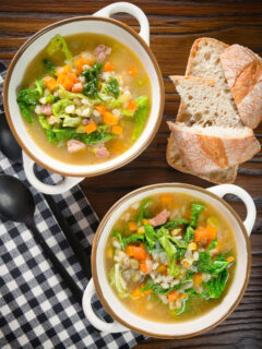 Overhead Scotch broth soup with lamb, pearl barley and savoy cabbage, served with bread.