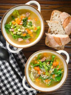 Overhead Scotch broth soup with lamb, pearl barley and savoy cabbage, served with bread.