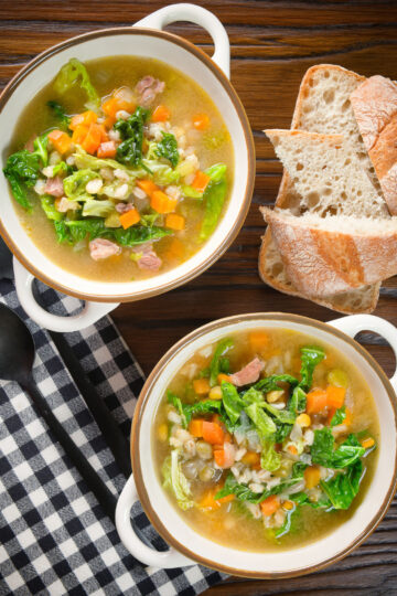 Overhead Scotch broth soup with lamb, pearl barley and savoy cabbage, served with bread.