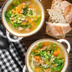 Overhead Scotch broth soup with lamb, pearl barley and savoy cabbage, served with bread.