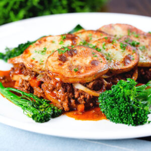 Minced beef and onion hotpot with a scalloped potato lid served with broccoli and fine beans.