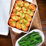Overhead minced beef and potato hotpot served in a baking dish with broccoli and green beans.
