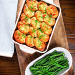 Overhead minced beef and potato hotpot served in a baking dish with broccoli and green beans.