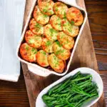 Overhead minced beef and potato hotpot served in a baking dish with broccoli and green beans.
