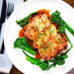 Overhead minced beef and onion hotpot with scalloped potatoes served with green veggies.