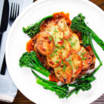 Overhead minced beef and onion hotpot with scalloped potatoes served with green veggies.