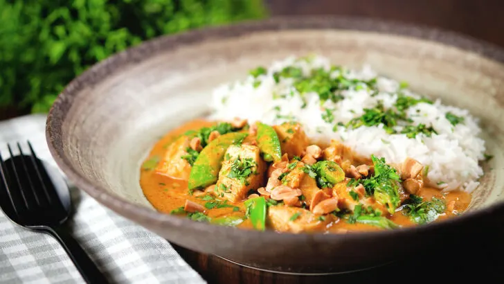 Satay chicken curry with sugar snap peas and peanuts served with rice and coriander.