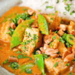 Close-up satay chicken curry with peanuts and coriander served with steamed rice.