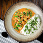 Satay chicken curry with sugar snap peas and peanuts served with rice and coriander.
