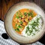 Satay chicken curry with sugar snap peas and peanuts served with rice and coriander.