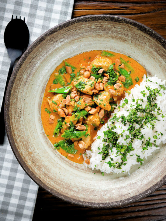 Overhead satay chicken curry with peanuts and coriander served with steamed rice.