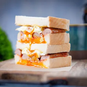 Simple sausage and fried egg breakfast sandwich served with coffee.