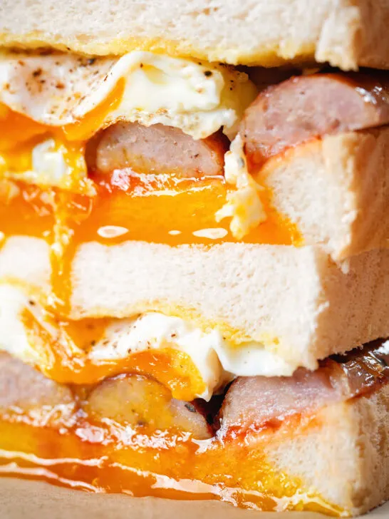 Close-up sausage and fried egg breakfast sandwich with a runny yolk.