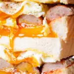 Close-up sausage and fried egg breakfast sandwich with a runny yolk.