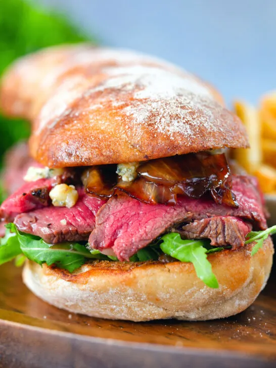 Close-up steak, stilton and caramelised onion sandwich served on ciabatta with french fries.