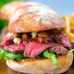 Close-up steak, stilton and caramelised onion sandwich served on ciabatta with french fries.