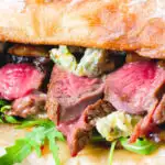Close-up steak, stilton, caramelised onion and rocket sandwich served on ciabatta.