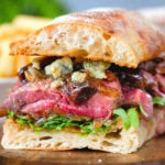 Cut in half, close-up steak, stilton, caramelised onion and rocket sandwich served on ciabatta.