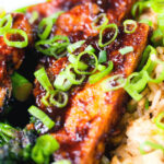 Close-up spicy fried tofu with black bean sauce and tenderstem broccoli served with egg fried rice.