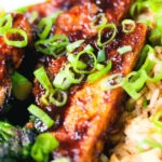 Close-up spicy fried tofu with black bean sauce and tenderstem broccoli served with egg fried rice.