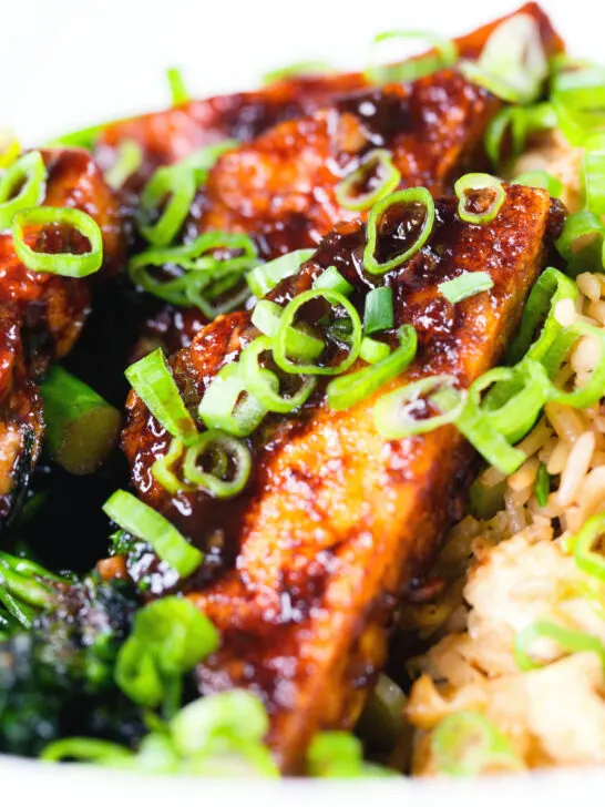 Close-up spicy fried tofu with black bean sauce and tenderstem broccoli served with egg fried rice.