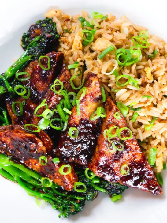 Close-up overhead spicy fried tofu with black bean sauce and tenderstem broccoli served with egg fried rice.