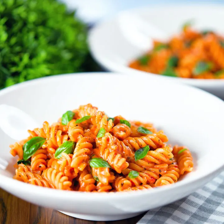 Creamy tomato, basil and mascarpone cheese pasta (fusilli) served in white bowls.