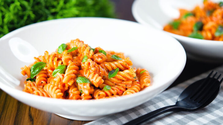 Creamy tomato, basil and mascarpone cheese pasta (fusilli) served in white bowls.