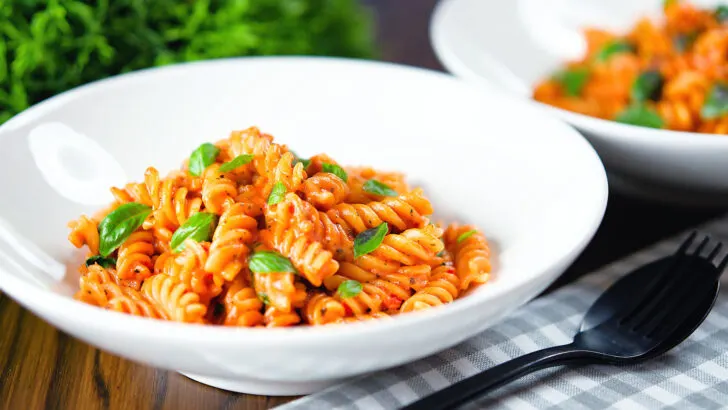 Creamy tomato, basil and mascarpone cheese pasta (fusilli) served in white bowls.