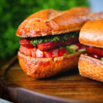 Close-up Argentinian-Influenced choripan sandwich with Spanish chorizo, chimichurri and salsa.