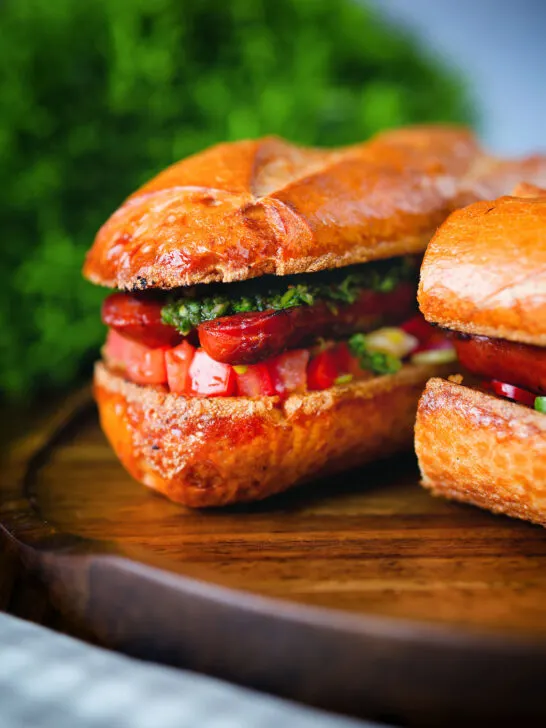 Close-up Argentinian-Influenced choripan sandwich with Spanish chorizo, chimichurri and salsa.