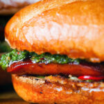 Close-up choripan sandwich with Spanish chorizo, chimichurri and salsa served on a crusty baguette.