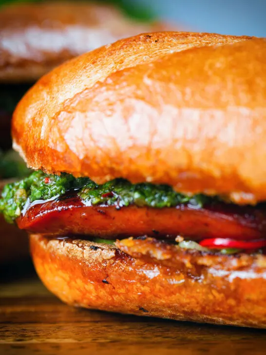 Close-up choripan sandwich with Spanish chorizo, chimichurri and salsa served on a crusty baguette.