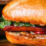 Close-up choripan sandwich with Spanish chorizo, chimichurri and salsa served on a crusty baguette.
