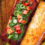 Overhead Argentinian-Influenced choripan sandwich with Spanish chorizo, chimichurri and salsa.