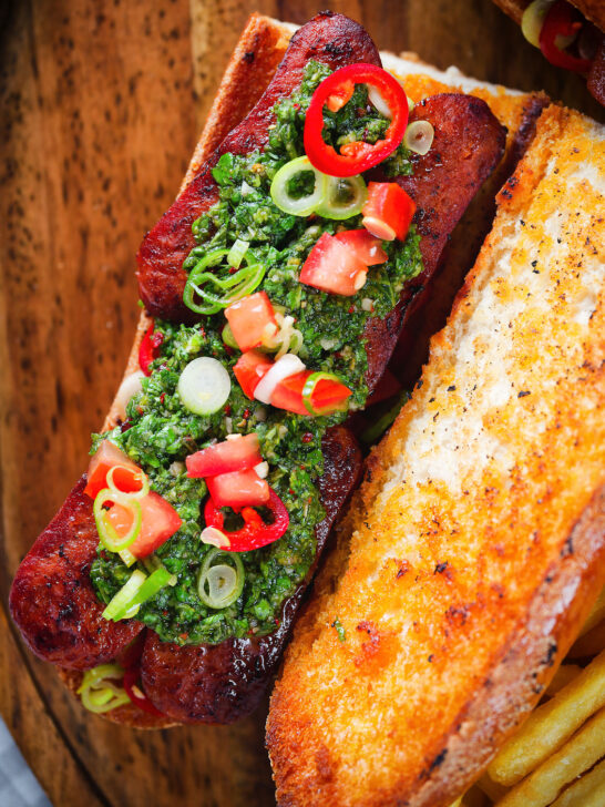 Overhead Argentinian-Influenced choripan sandwich with Spanish chorizo, chimichurri and salsa.