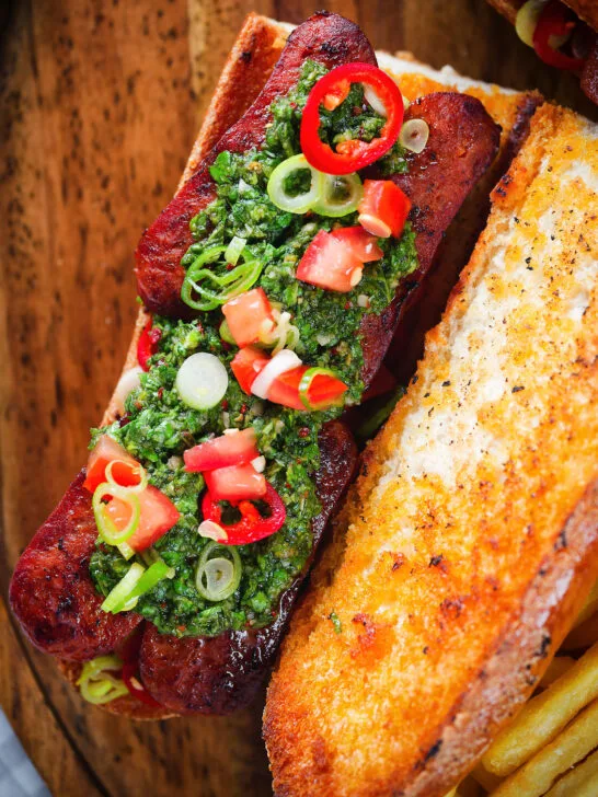 Overhead Argentinian-Influenced choripan sandwich with Spanish chorizo, chimichurri and salsa.