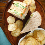 Overhead canned crab sandwiches with coriander, lime and chilli mayonnaise serve with crisps.