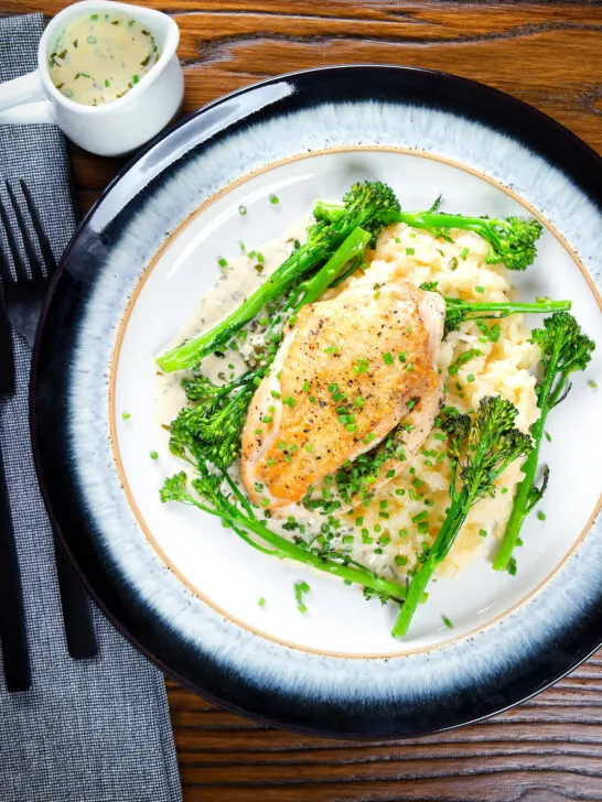 Overhead creamy tarragon chicken breasts served with celeriac mash and tenderstem broccoli.