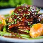 Close-up devilled chicken thighs served with roasted new potatoes, green beans and chives.