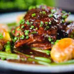 Close-up devilled chicken thighs served with roasted new potatoes, green beans and chives.