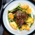 Overhead devilled chicken thighs served with roasted new potatoes, green beans and chives.