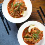 Overhead chicken chasseur or French hunters chicken served with mashed potato in two bowls.