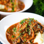 Chicken chasseur or French hunters chicken served with mashed potato in two bowls.