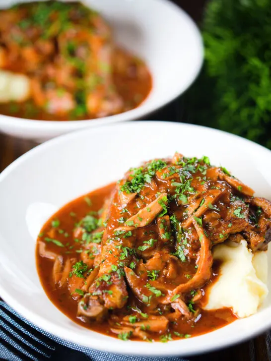 Chicken chasseur or French hunters chicken served with mashed potato in two bowls.